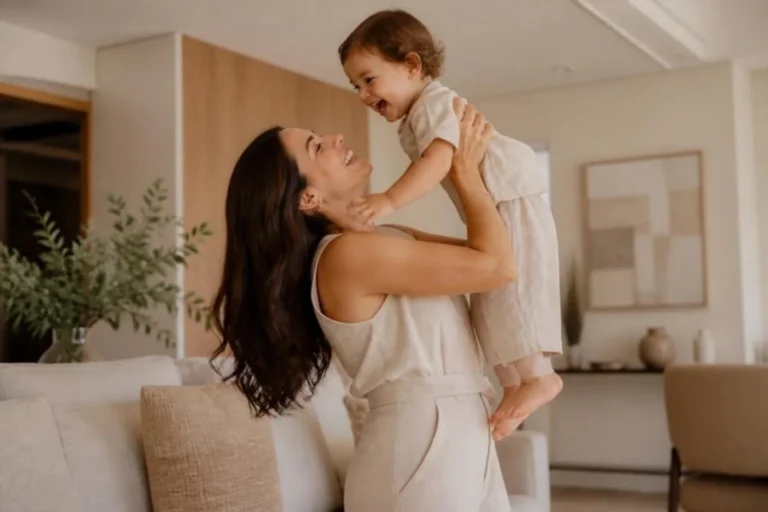 Mãe sorrindo e levantando o filho no colo em casa